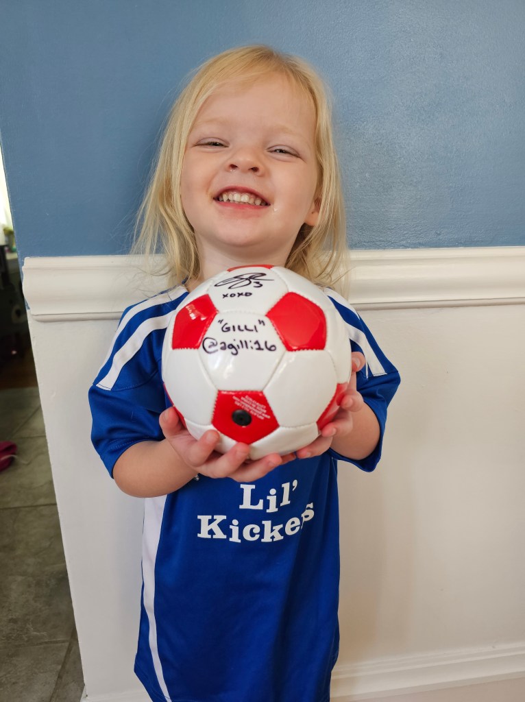 A proud Charlie with her signed Arin Wright ball and her soccer uniform